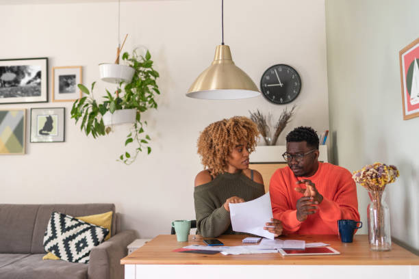 The couple planning their home budget A young African-American couple sits at the dining table and calculates their home finance. They look a bit worried because of the tight budget. expense photos stock pictures, royalty-free photos & images