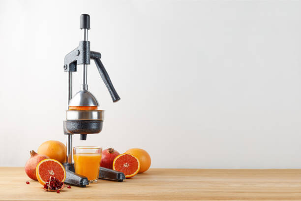 istock Juicer for citrus fruits with different fruits, red orange, grapefruit, pomegranate.  Freshly squeezed juice in glass on wooden table. Juicer press 1368381786
