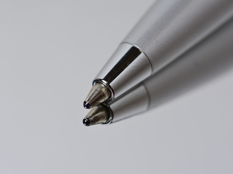 ballpoint pen for signature on a mirror surface. On a gray background, macro tip