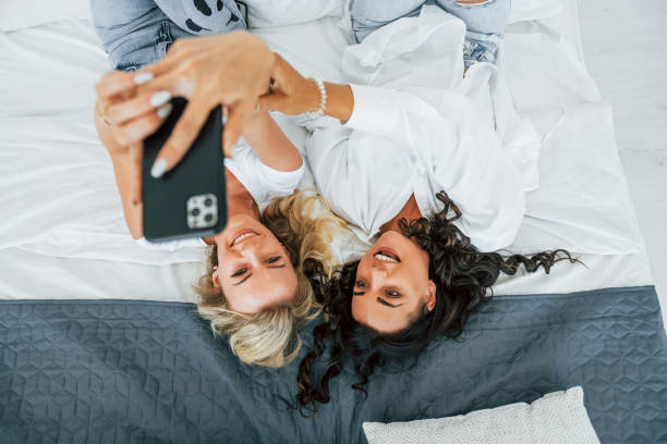 istock Upside down view. Laying down on bed. Two women is together at home 1368386174