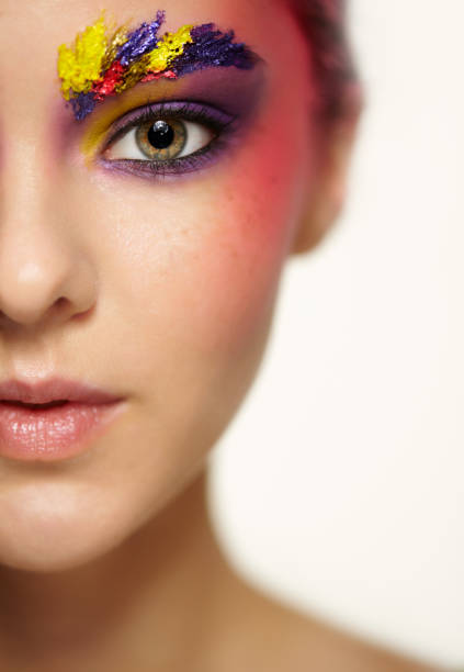 Close-up female portrait with half face and with shallow depth of focus. Unusual art make-up with paint on brows and around eyes.