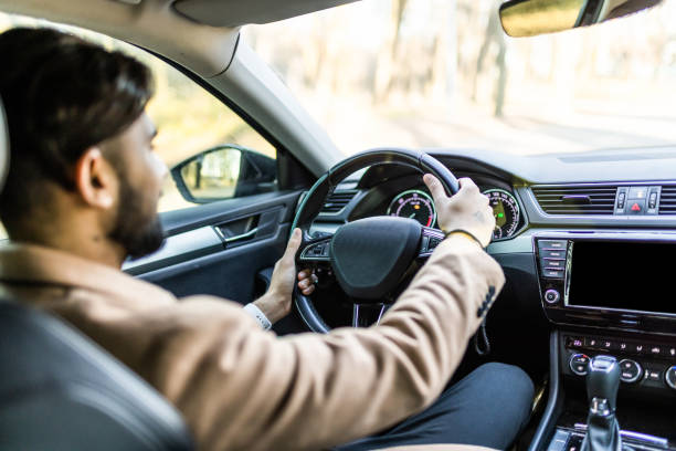 istock Success in motion. Handsome indian young man in full suit smiling while driving a car 1368389729