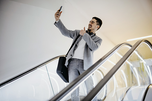 image of mid adult man taking selfie on escalator