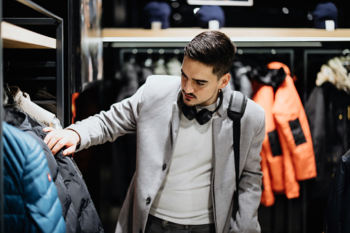 Portrait of handsome young man buying clothes in the store.sale, shopping, fashion, style and people concept - happy young man  choosing clothes in mall or clothing store