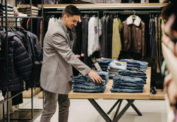 istock Young man chooses clothes in shop 1368390746