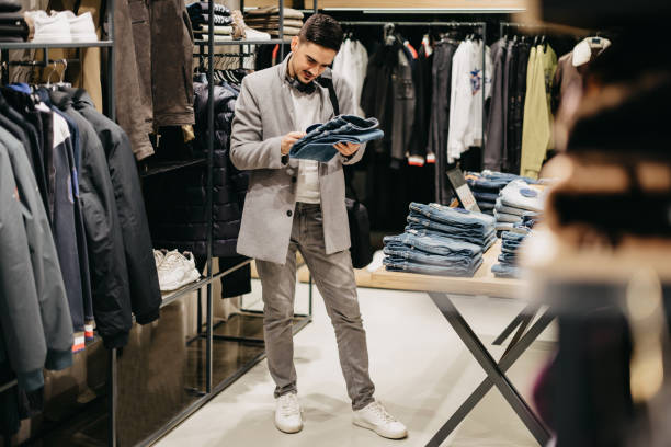 istock Young man chooses clothes in shop 1368390747