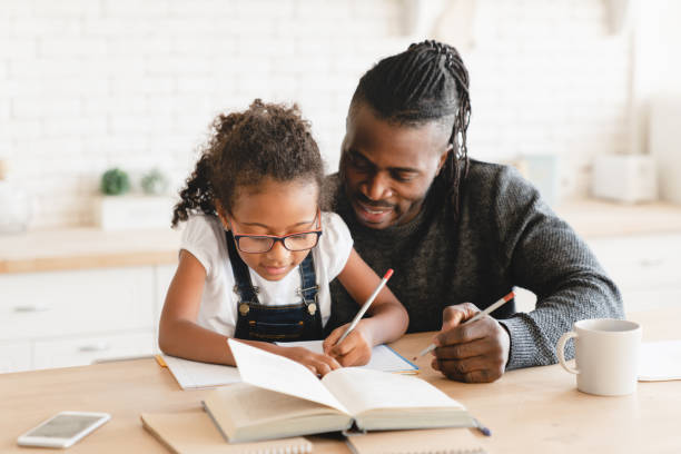 afroamerikanischer vater vater tutor tagesmutter hilft bei der hausaufgaben-schulprojekt für eine preteen tochter schüler. homeschool-konzept. e-learning - ein elternteil stock-fotos und bilder