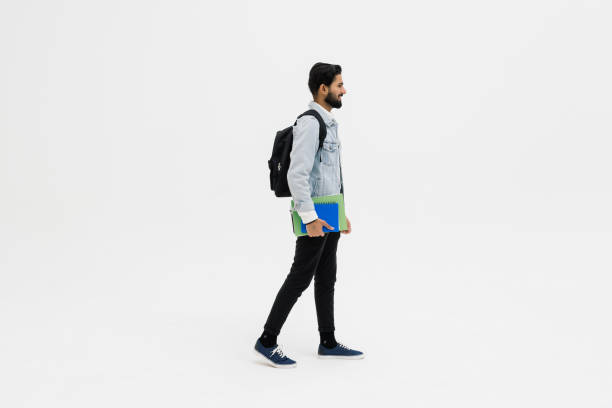 istock Smiling indian student standing with textbooks and backpack on white background 1368395519