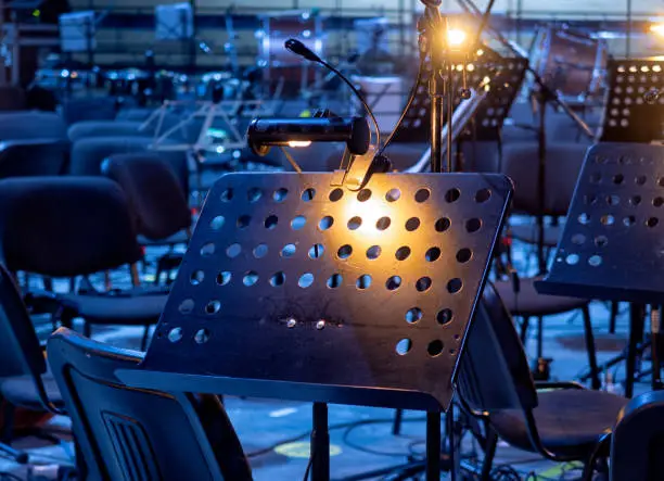 Photo of Before the concert the orchestra gathers, the music stands on the ground.