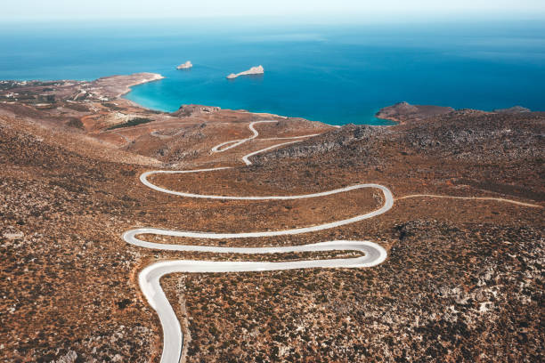 Curvy Road To The Sea Aerial view on winding mountain road towards Xerokampos (Crete, Greece). rocky coastline stock pictures, royalty-free photos & images