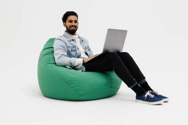 istock Young man holding notebook browsing chatting colleagues sitting comfy soft armchair wear specs casual denim outfit isolated grey color background 1368398112