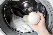 istock Woman using wool dryer balls for more soft clothes while tumble drying in washing machine concept. Discharge static electricity and shorten drying time, save energy. 1368398173