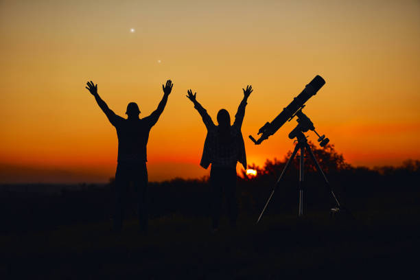 istock Couple stargazing together with a astronomical telescope. 1368399195