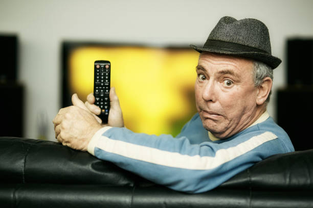 istock Elderly man looks shocked and horrified as he holds his remote control while watching TV 1368399501