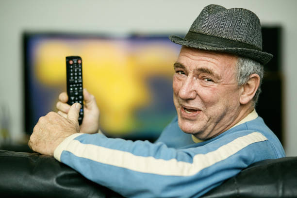 istock Elderly man smiles contentedly as he holds ihis remote control while watching TV 1368399536