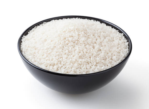 istock Uncooked round rice in black bowl isolated on white background with clipping path 1368401140