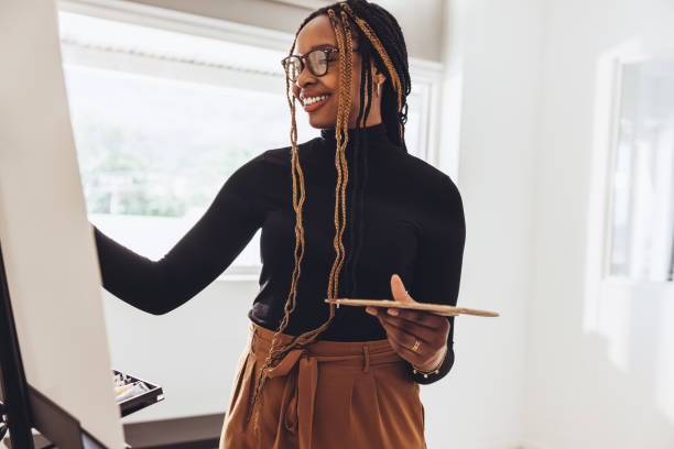 istock Smiling painter working on a painting in her art studio 1368402235