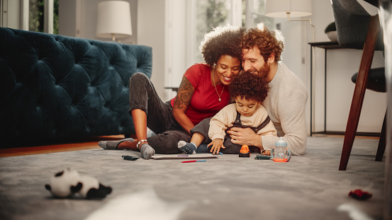 Loving Mixed Race Family Playing with Toys with Adorable Baby Boy at Home on Living Room Floor. Cheerful Mother and Father Nurturing a Child. Concept of Childhood, New Life, Parenthood.