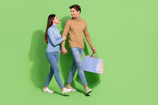 Photo of lovely shopaholic couple carry bargains enjoy store retail wear casual outfit isolated green color background.