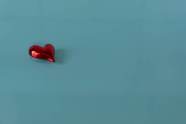 istock Isolated red shiny heart on turquoise glass background. 1368403461