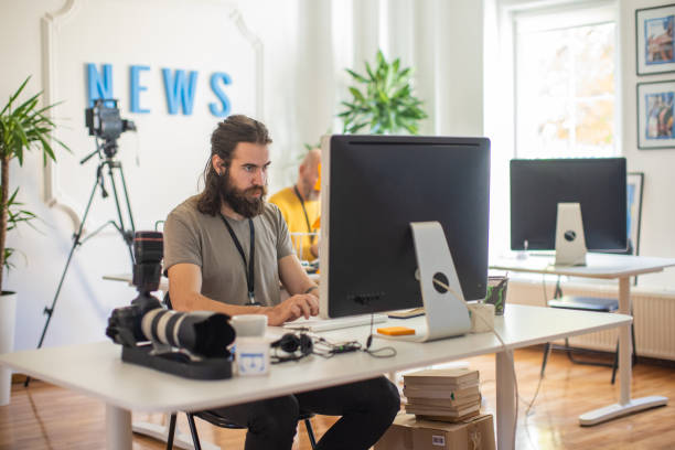 Focused Caucasian male journalist, working on computer at the editorial office