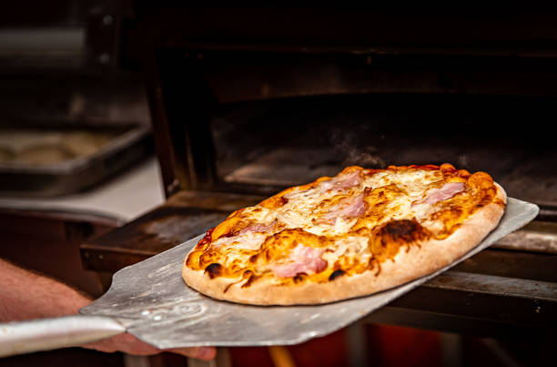 istock chef baker making pizza at kitchen. Put on landing shovel and send it to the oven. 1368406364