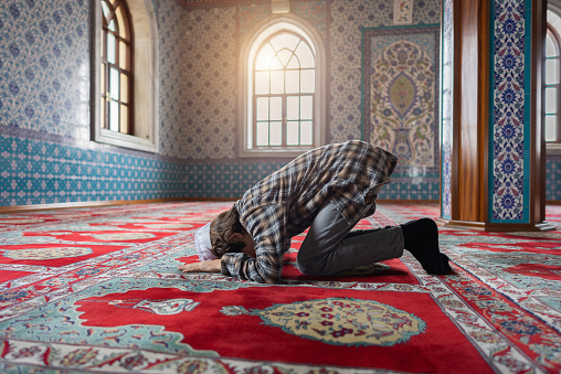 The Muslim young boy prays in the mosque, the young boy prays to God, Peace and love in the holy month of Ramadan.