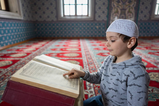 Lİttle muslim boy reading The Holy Koran in Mosque stock photo