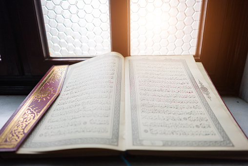 Open dark book (Bible) laying on a wooden background with room for text