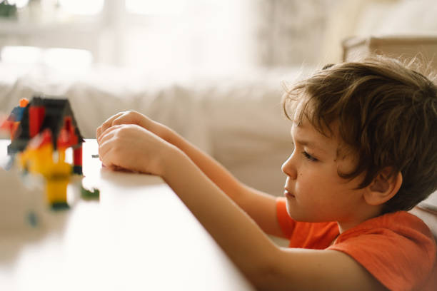 istock Cute boy is playing constructor at home. Kid playing block toys in home at nursery. 1368409474
