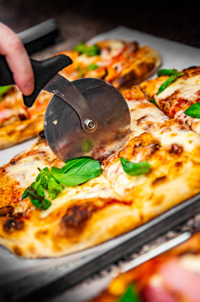 istock chef hand with cutter cutting pizza to pieces at pizzeria 1368409544