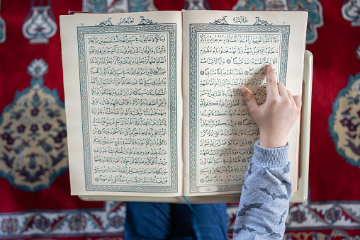 Close up boy hand reading The Holy Koran