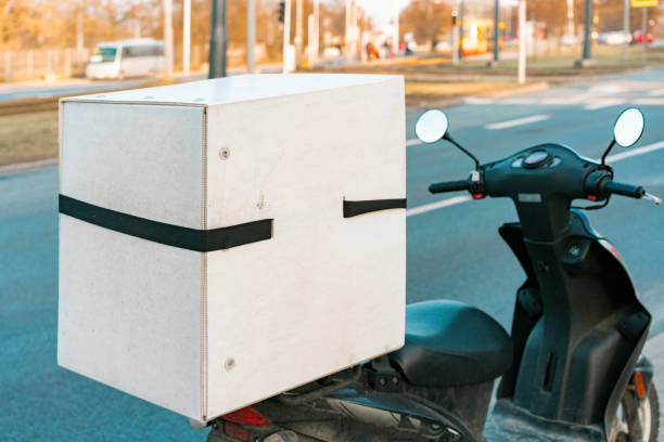 istock White delivery box installed on a motorcycle stands on the road. Service. Delivering. Transportation. Urban. City. Business. Vehicle 1368410738