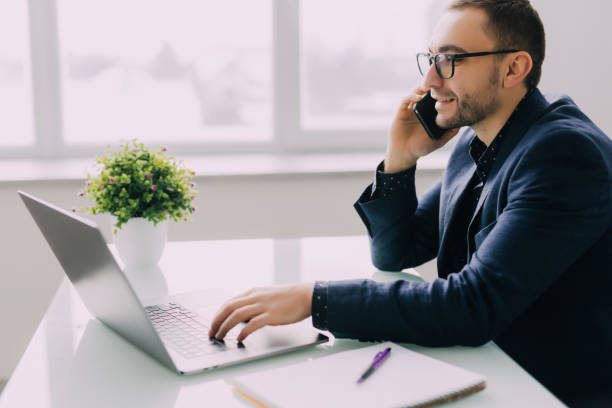 istock Young businessman talking on cell phone and using laptop in office 1368412226
