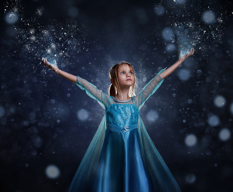 Young girl snow princess. Mystery fantasy girl in blue lush dress. Art background winter frozen and snow.