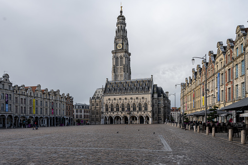 Arras, France - November 4, 2021: Town square of Arras, France. UNESCO World Heritage Site, the Belfry of Arras, against a dark grey sky