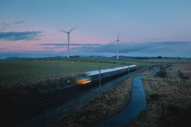 Moving blurred train across countryside and windmills in the evening