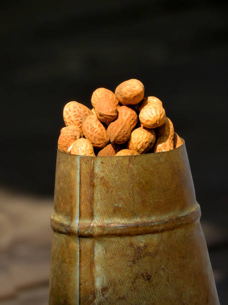 peanuts or groundnuts on an antique Hand Crafted Iron Grain Measurement Pot. stock photo