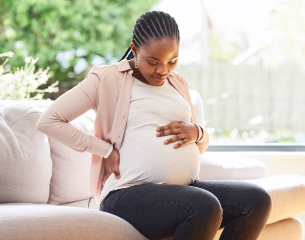 집에서 소파에 앉아있는 동안 불편해 보이는 매력적인 젊은 어머니의 자른 샷 - human pregnancy 뉴스 사진 이미지