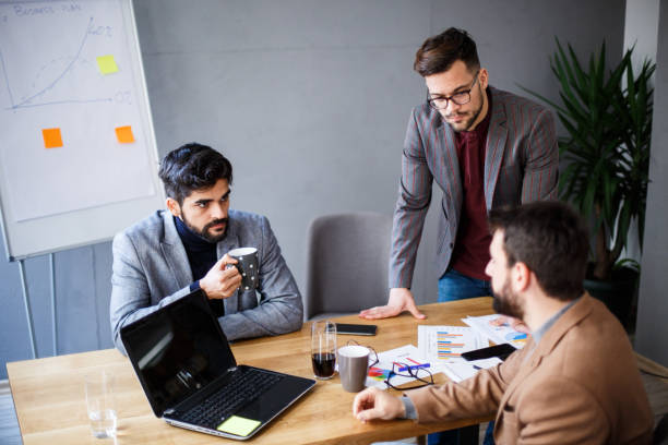 istock Three office workers are sitting at the table and talking. They are smiling and talking. 1368414807