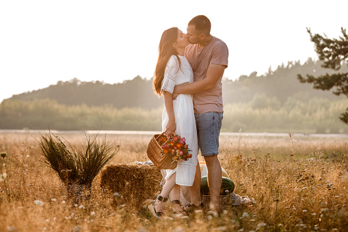 young happy couple in love kissing and hugging on nature. Man and woman hugging, sunlight in summer meadow. Happy family in the evening sun light. The concept holiday. valentine's day.