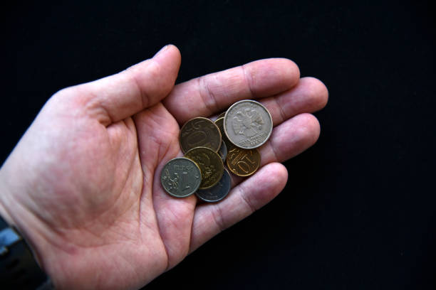 istock An outstretched hand with coins on a black background 1368417068