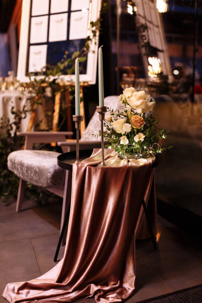 istock festive Decor. Details. white long candles on gold candlesticks. flower composition with white, yellow, pink flowers and greenery on the black metal table and pink tablecloth. Wedding decorations 1368418634