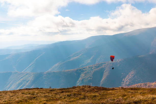 parapendio in altopiano contro gigantesche montagne forestali - outdoors nature paragliding autumn foto e immagini stock