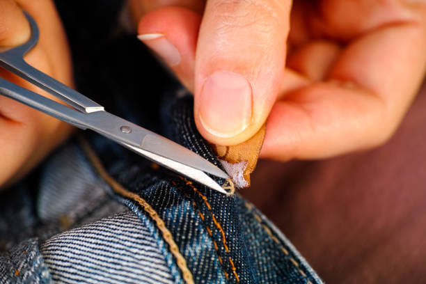 istock Woman hands cutting a tag off jeans using a scissors. 1368419600