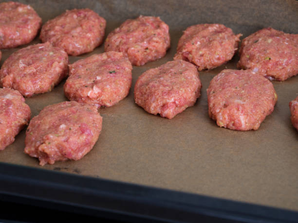 istock Raw meat cutlets on parchment paper in a baking sheet 1368419651