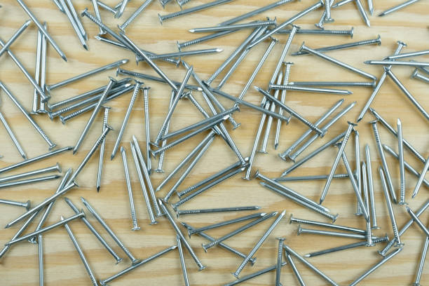 A pile of Small nails scattered on a wood bg. Close up, top view. A pile of Small nails scattered on a wood bg. Close up, top view. rustproof stock pictures, royalty-free photos & images