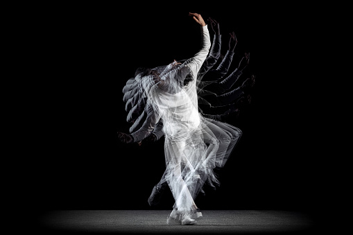 White and black. Young man, hip-hop dancer in action, motion isolated on dark background with sroboscope effect. Youth culture, hip-hop, movement, style and fashion. Modern street dancing style