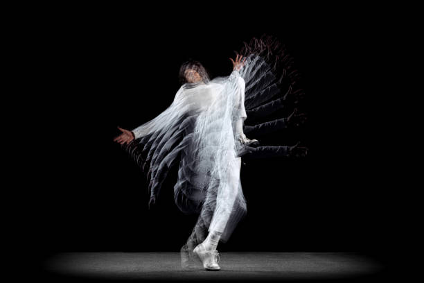 White and black. Young man, hip-hop dancer in action, motion isolated on dark background with sroboscope effect. Youth culture, hip-hop, movement, style and fashion. Modern street dancing style