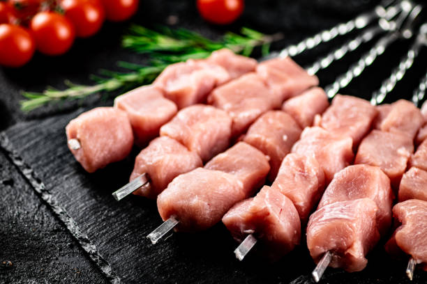 istock Pork kebab raw with tomatoes on a stone board. 1368422343